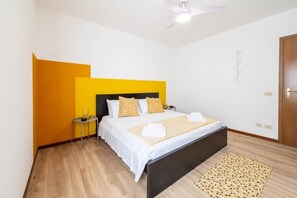 A bedroom with a bed, bedside table, and a ceiling fan.