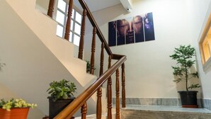 Una escalera con barandilla de madera, plantas en macetas y una obra de arte en la pared.