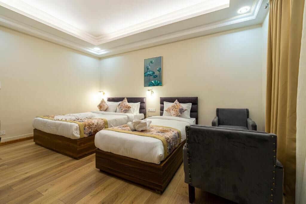 Una habitación de hotel con dos camas, una silla y un cuadro en la pared.