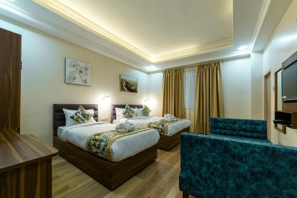Habitación de hotel con dos camas, televisión, escritorio y una silla.