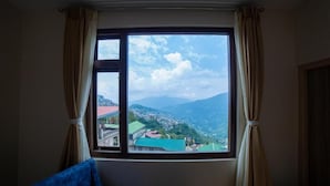 Una habitación con un gran ventanal, cortinas y vistas a un paisaje montañoso.