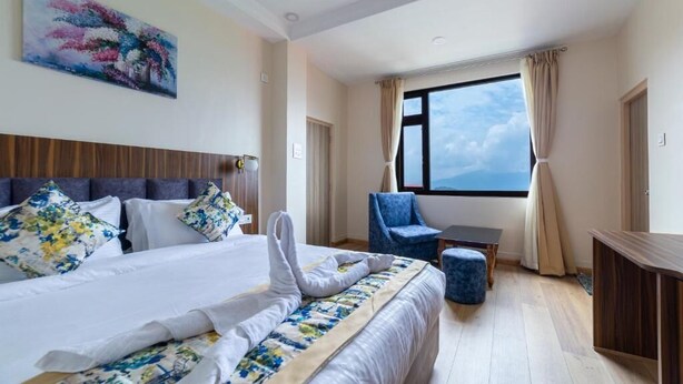 Una habitación de hotel con una cama, una silla, una mesita pequeña y un ventanal grande.