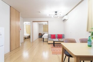 A compact living space with a kitchenette, a dining area, a sofa, and a bed. - SEED Tanimachi 6-chome (Osaka)