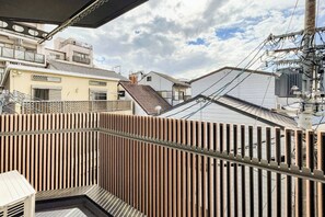 A residential building with a wooden fence, a balcony, and a view of neighboring houses. - SEED Tanimachi 6-chome (Osaka)