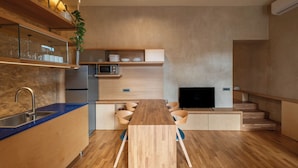 A modern kitchen with a wooden countertop, built-in microwave, and a TV on a wooden stand. - Ismini House (Chania)