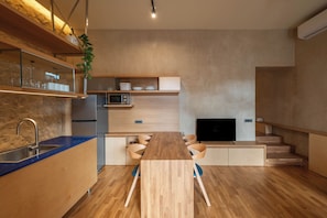 A modern kitchen with a wooden countertop, built-in microwave, and a TV on a wooden stand. - Ismini House (Chania)