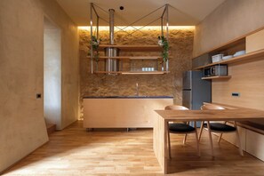 A modern kitchen with a wooden table, chairs, and built-in appliances. - Ismini House (Chania)