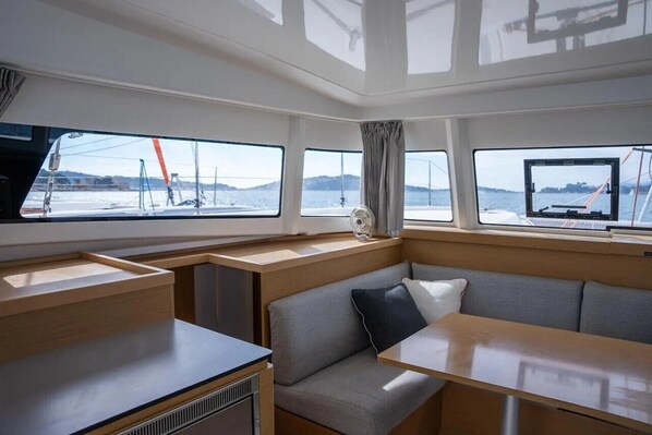 L’intérieur d’un bateau comprend un espace repas, des sièges et des fenêtres offrant une vue sur l’eau.
