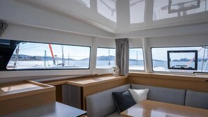 Veneen sisätilat, joissa on ruokailutila, istuimia ja ikkunat, joista on näkymä vesistöön.