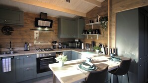 Una cocina moderna con techo de madera, electrodomésticos integrados y un comedor con mesa y sillas.