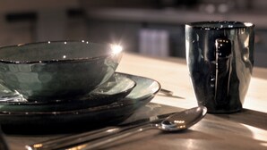 Una mesa de comedor con un tazón, una taza y una cuchara.