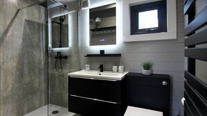Un baño moderno con cabina de ducha de vidrio, un lavabo con espejo y un inodoro.