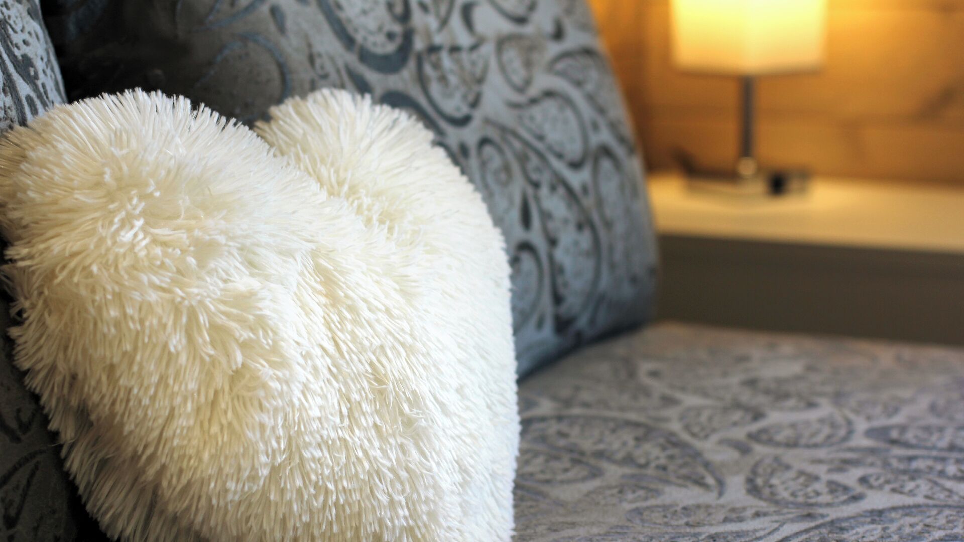 Ein Sofa mit einem gemusterten Kissen und einem flauschigen weißen Kopfkissen.