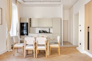 Eine moderne Küche mit weißen Schränken, einem Esstisch mit vier Stühlen und einem eingebauten Backofen.