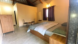 A bedroom with a bed, a wooden nightstand, a desk with two chairs, and a wardrobe. - Mountain View Villa - Mulshi (Paud)