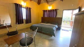 Un dormitorio con cama, una silla, una mesa y un balcón.