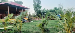 A house with a red roof, a porch, and a well-maintained lawn with various plants. - Mountain View Villa - Mulshi (Paud)