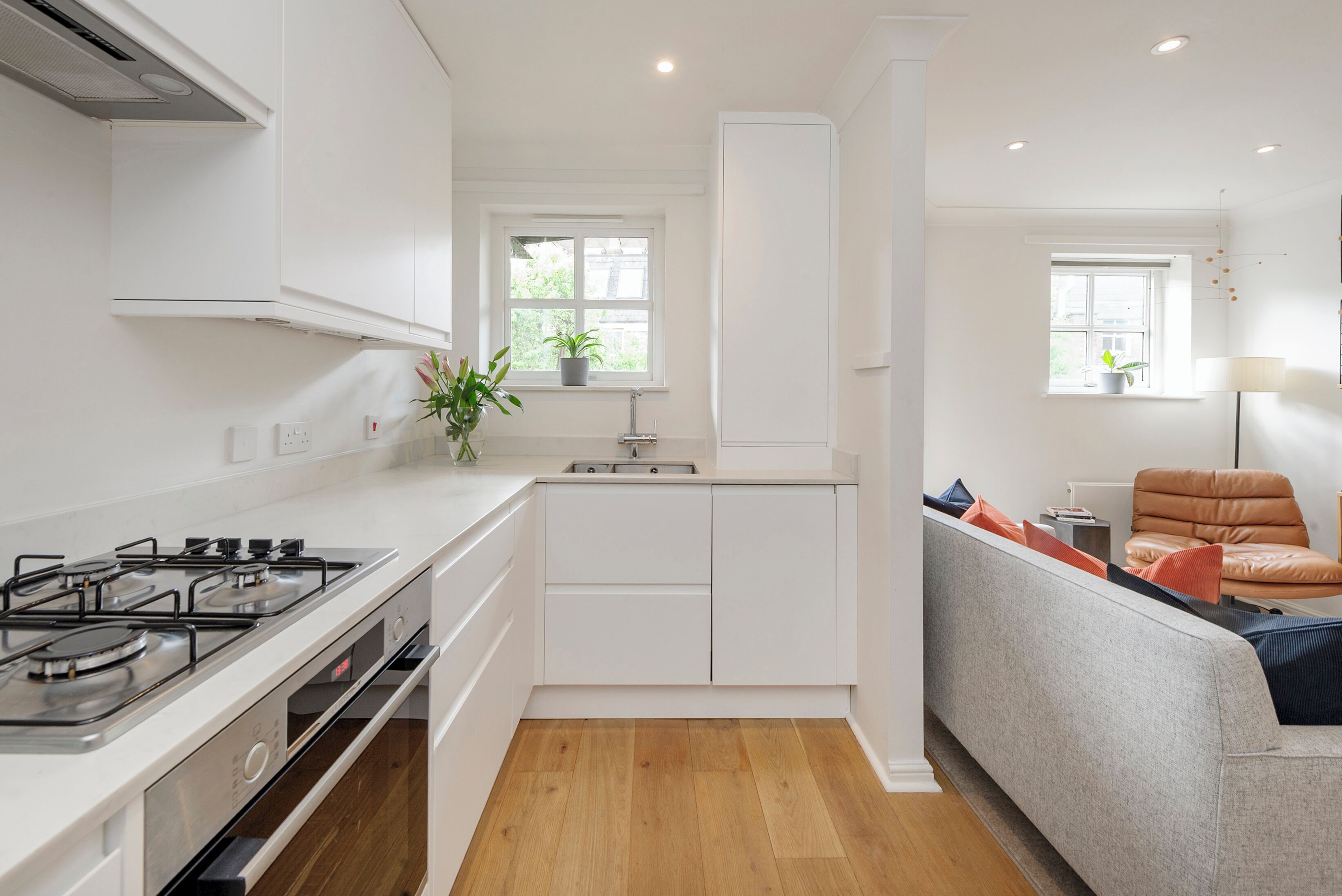 A modern kitchen with white cabinetry, a gas stove, and a window with a plant.