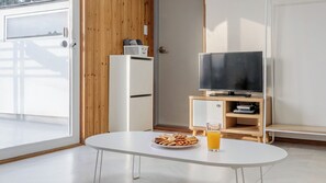 A modern room with a white table, a television, and a snack plate. - Gangneung Good Camping Caravan Pension (Gangneung)