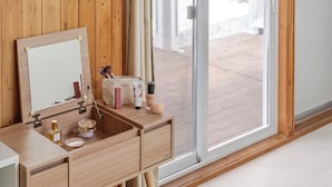 Een houten wastafelmeubel met een spiegel, een klein wastafeltje en een make-up tas.