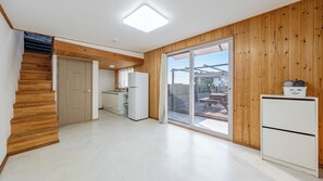 A modern kitchen with a built-in oven, a dining area with a table and chairs, and a wooden staircase. - Gangneung Good Camping Caravan Pension (Gangneung)