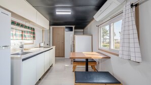 Een kleine keuken met een houten tafel, een gootsteen en een raam met gordijnen.