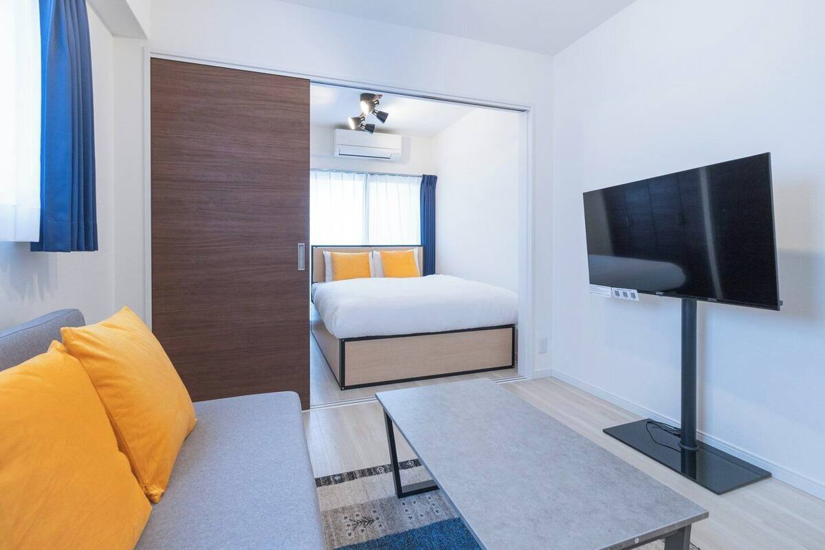 A hotel room with a bed, a TV, a sofa, and a desk.