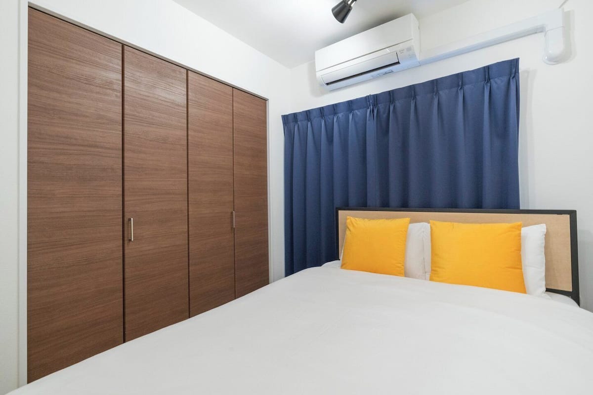 A bedroom with a bed, a wardrobe, and an air conditioning unit.