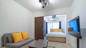 A modern hotel room with a sofa, bed, TV, and a ceiling fan. - Curasion Oyodonaka (Osaka)
