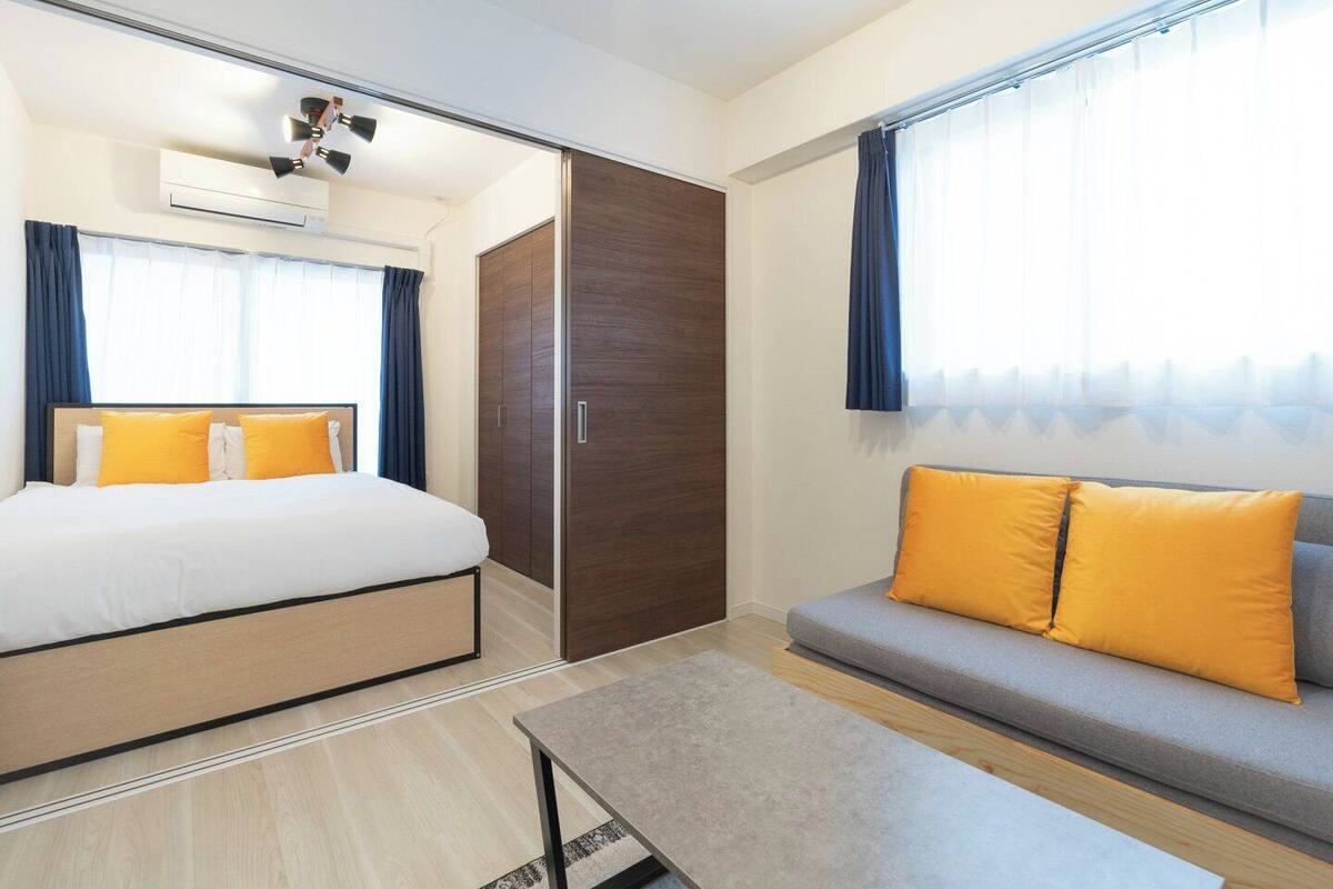 A hotel room with a bed, a sofa, a table, and a wardrobe.