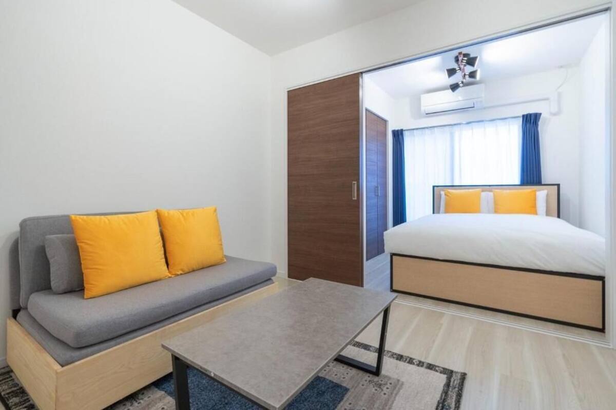 A modern hotel room with a sofa, a bed, a small table, and a wardrobe.