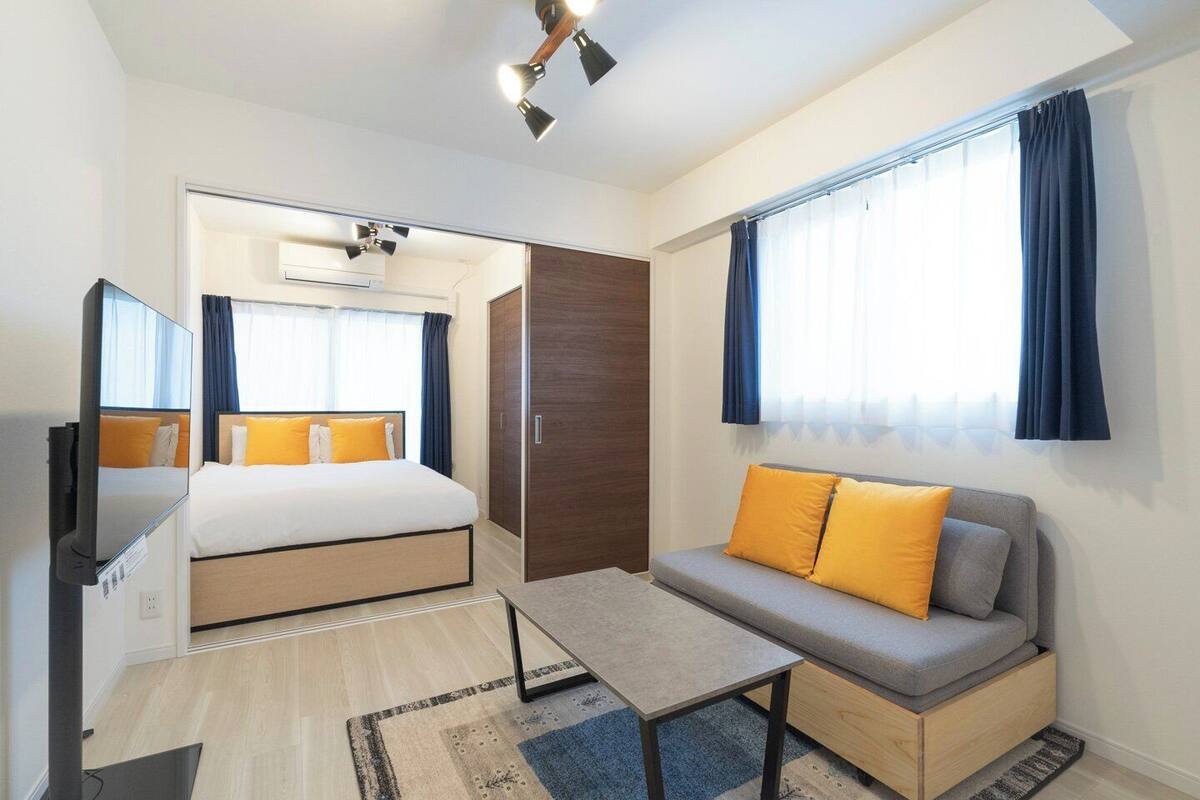 A hotel room with a bed, a sofa, a small table, a mirror, and a wardrobe.