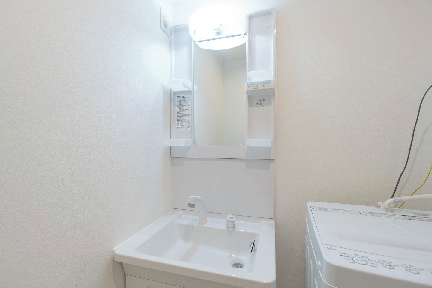 Une petite salle de bain blanche, avec un lavabo, un miroir et un meuble blanc au-dessus du lavabo.