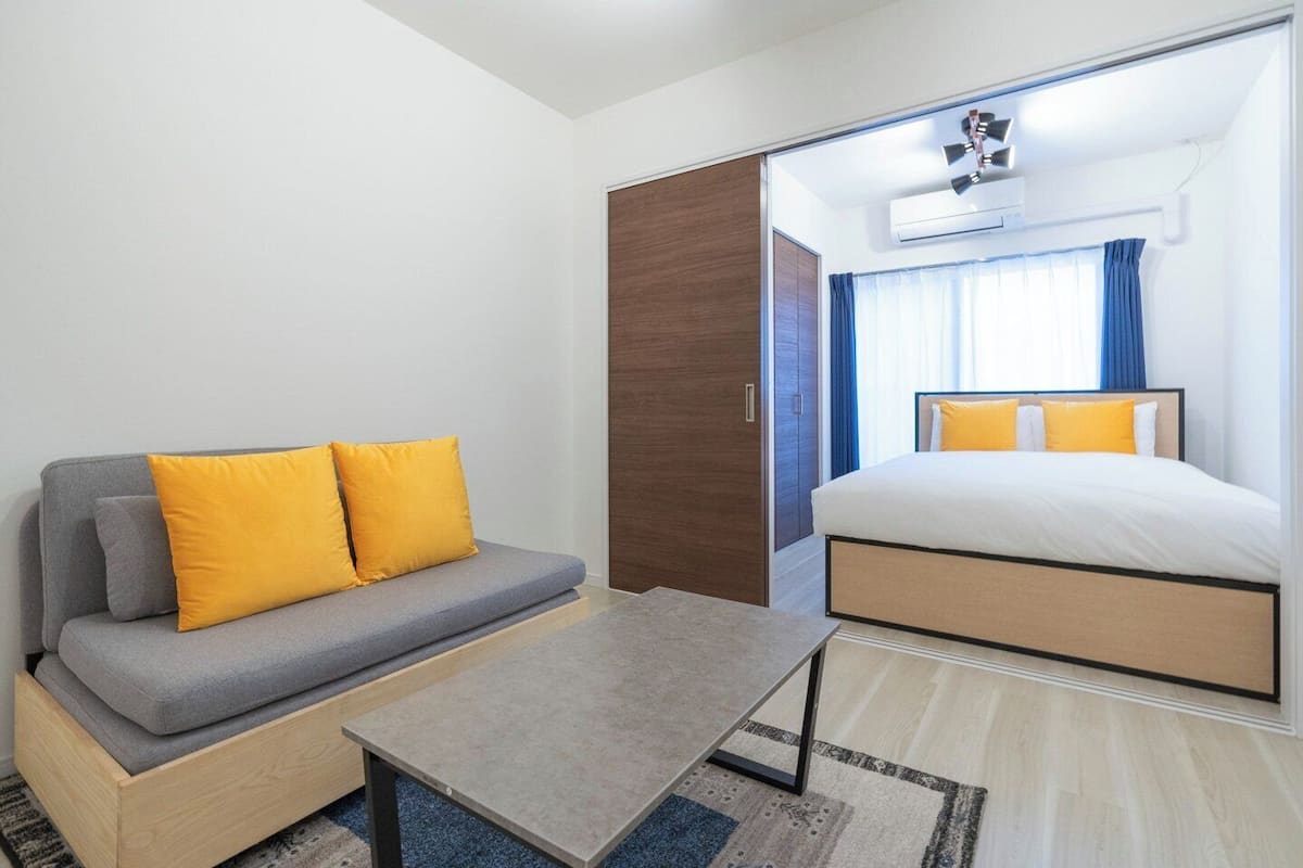 A modern hotel room with a sofa, bed, and a small table.