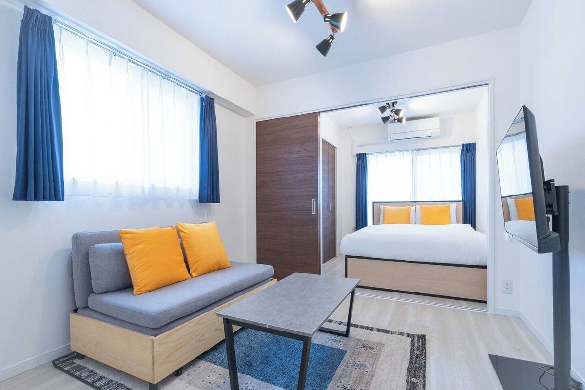 A modern hotel room with a sofa, a bed, a small table, and a television.