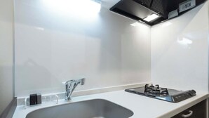 A modern kitchen with a stainless steel sink, a gas stove, and a sleek countertop. - Curasion Oyodonaka (Osaka)