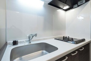 A modern kitchen with a stainless steel sink, a gas stove, and a sleek countertop. - Curasion Oyodonaka (Osaka)
