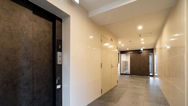 A modern hallway with a marble floor, a wall-mounted elevator, and a door leading to a room with a view. - Curasion Oyodonaka (Osaka)