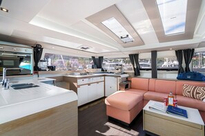A modern kitchen with a built-in oven and a dining area with a sofa and a table. - Caribbean Dream: Sun-soaked Sailing Adventure from Tortola, Islas Vírgenes Británicas (Road Town)