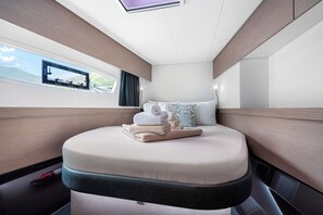 A compact, well-lit cabin with a bed, pillows, and neatly folded towels. - Caribbean Dream: Sun-soaked Sailing Adventure from Tortola, Islas Vírgenes Británicas (Road Town)