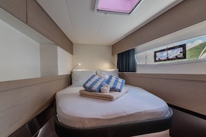 Ein modernes Schlafzimmer mit Bett, Kissen, einem Nachttisch, einem Fenster mit Blick und einer Deckenleuchte.