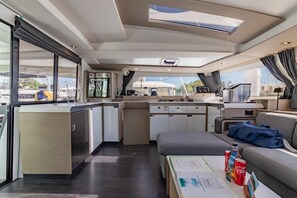 Eine moderne Kombüchenzeile mit einer zentralen Kochinsel, einer Sitzecke mit Tisch und Blick durch die Fenster.