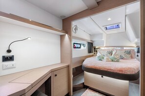 Een compacte, moderne kamer met een bed, een bureau, een spiegel en een kleine televisie.