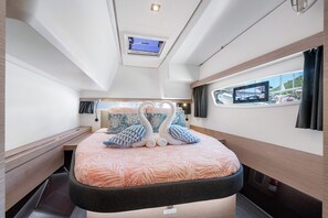 Un dormitorio con cama, tragaluz, ventana y vista al mar.