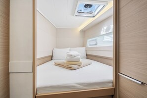 Ein kompakter, gut beleuchteter Raum mit einem Bett, einem Oberlicht und einem kleinen Fenster.