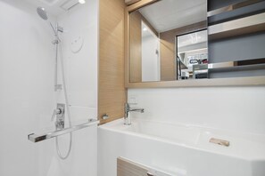 A modern bathroom with a shower, a bathtub, and a mirror reflecting a kitchen area. - Caribbean Dream: Sun-soaked Sailing Adventure from Tortola, Islas Vírgenes Británicas (Road Town)