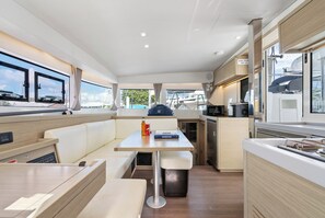 A compact kitchen with a dining area, a small trash bin, and a window with a view of boats. - Caribbean Dream: Sun-soaked Sailing Adventure from Tortola, Islas Vírgenes Británicas (Road Town)