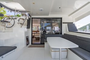A modern boat interior with a dining area, seating, and a view of the outside. - Caribbean Dream: Sun-soaked Sailing Adventure from Tortola, Islas Vírgenes Británicas (Road Town)