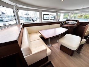 A boat interior with a seating area, a table, and a control panel.