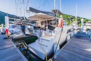 Eine Yacht liegt in einer Marina vor Anker, mit einem überdachten Deckbereich, dem Namen 'Jempre Verde' auf dem Bug und der Webseite 'evergreen.com'.
